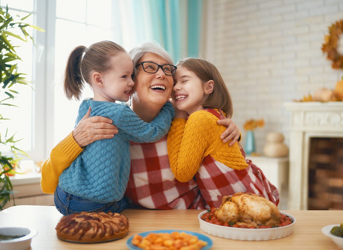 Medicare - Happy Grandmother Embracing Grandchildren at the Family Dinner Table
