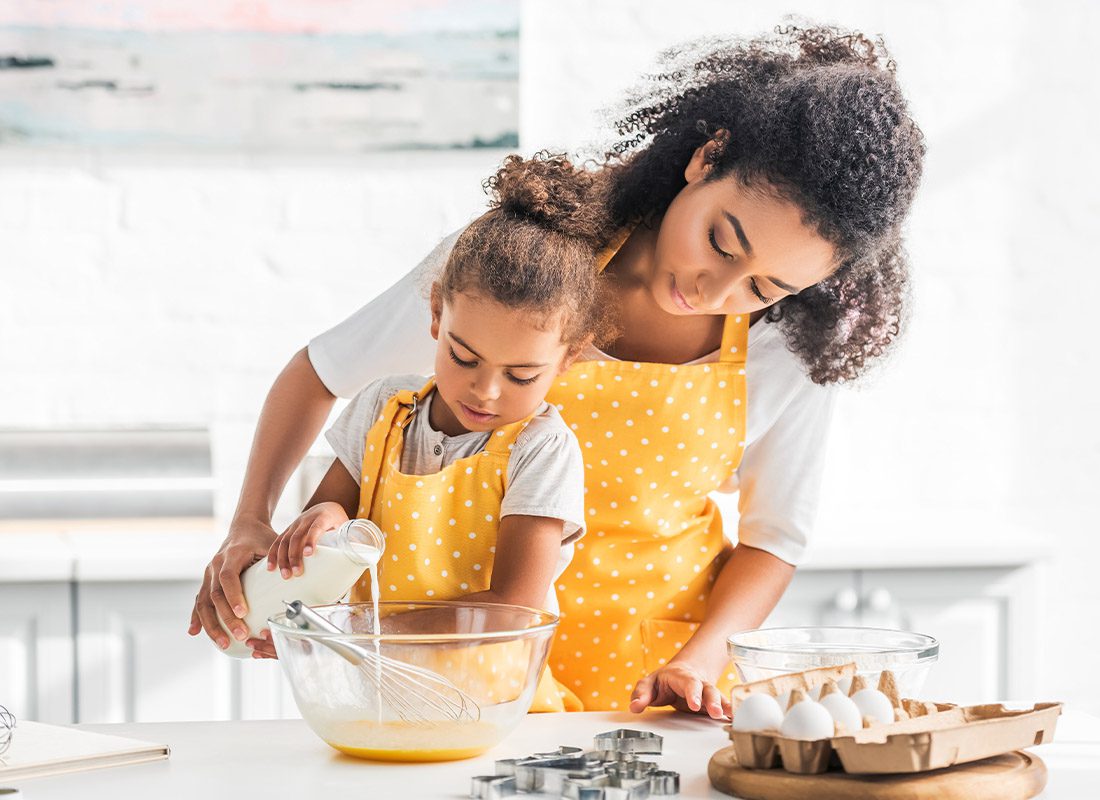 Personal Insurance - Mother and Daughter Preparing Dough and Pouring Milk Into Bowl in Kitchen
